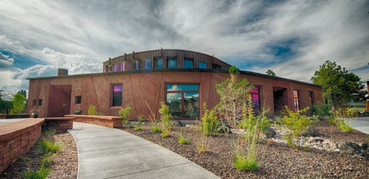 The round, rust-colored Native American Cultural Center building at Northern Arizona University under a cloudy sky
