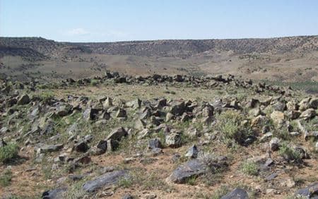 The Cross Canyon Stone Circle, a ring of scattered stones on a ridge with a mesa on the horizon